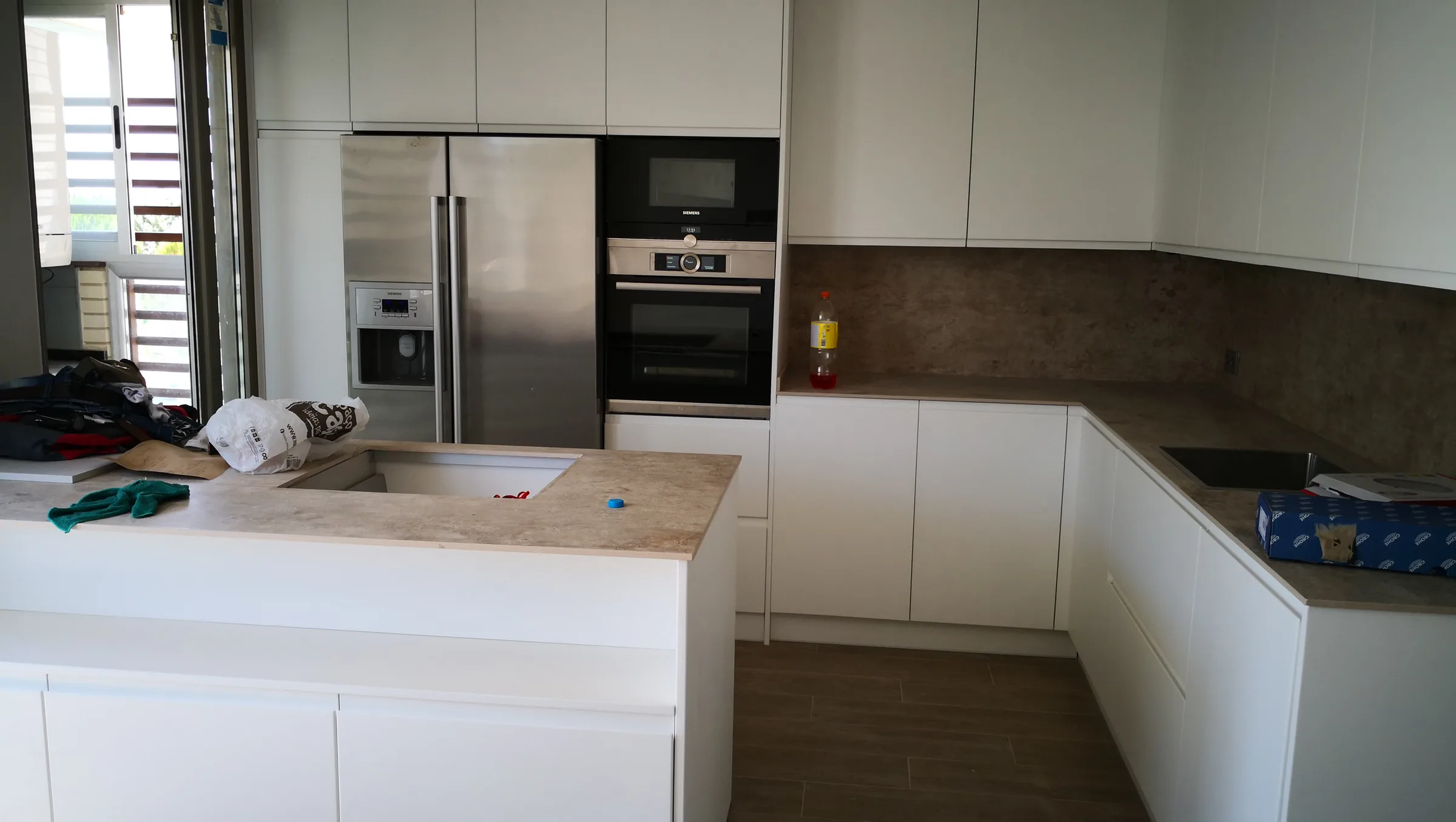 Cocina blanca en U con isla central, frigorífico americano y horno integrados en columna