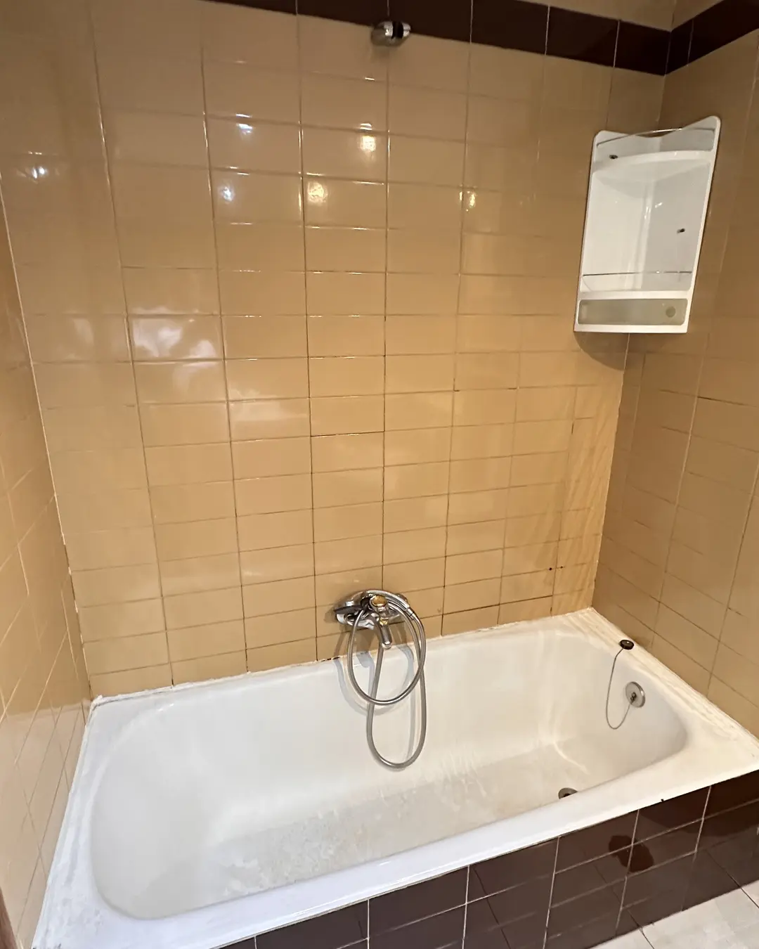 Baño antiguo con bañera y azulejo color crema de los años 80, antes de la reforma