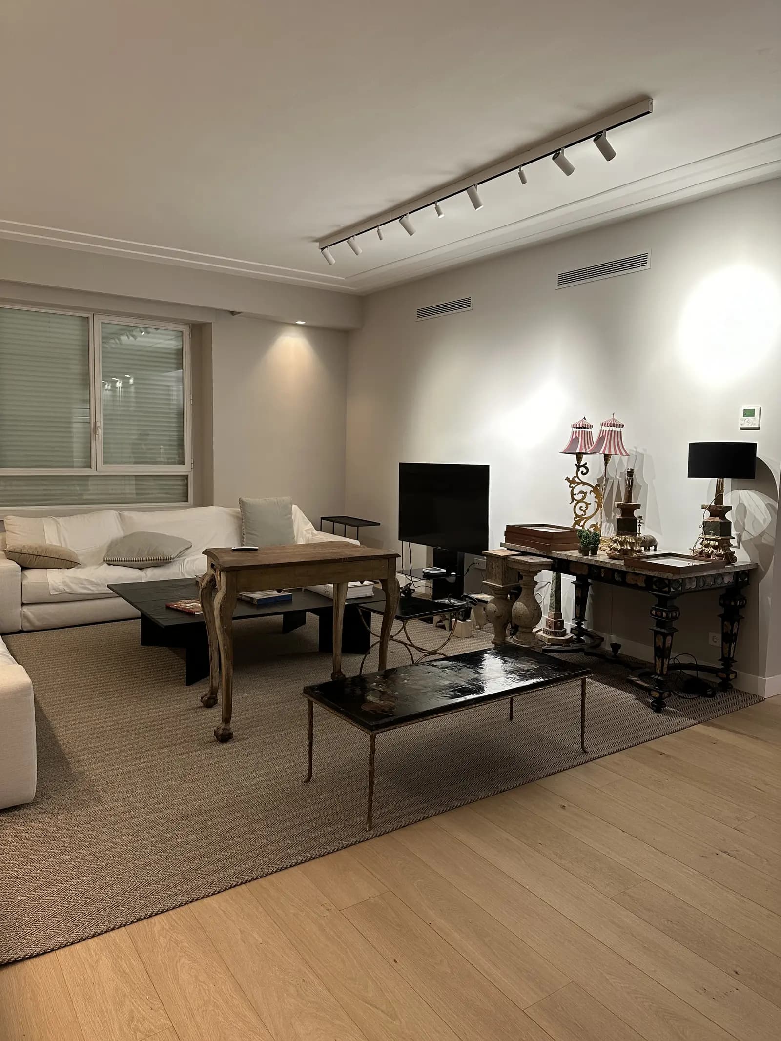 Salón reformado con suelo de parquet claro e iluminación técnica de carril integrada en el techo